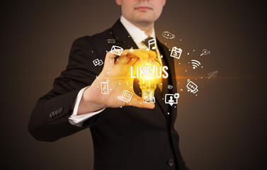 Businessman holding light bulb with LIKE US inscription, social media concept