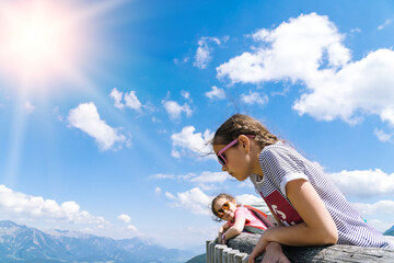 Children hiking on beautiful summer day in alps mountains Austria, resting on rock and admire amazing view to mountain peaks. Active family vacation leisure with kids. Outdoor fun and healthy activity