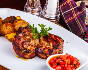 Grilled meat with baked potato and tomato on white plate