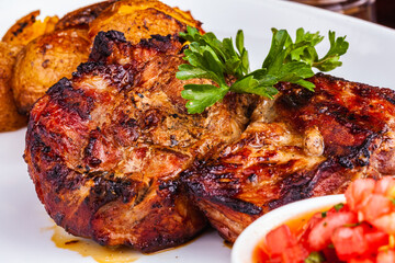 Grilled meat with baked potato and tomato on white plate