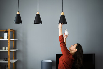 Woman Changing Broken Light Bulb