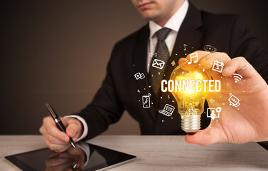 Businessman holding light bulb with CONNECTED inscription, social media concept