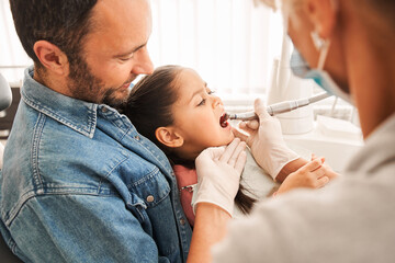 Girl sitting with her father at paediatric dentist office