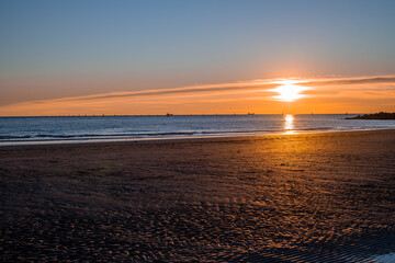 sunset at sea, sun on the same level with the sea and casual passers-by on the run