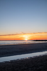 sunset at sea, sun on the same level with the sea and casual passers-by on the run