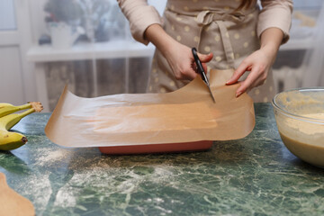 Woman cut baking paper for ceramic form, cooking baking.