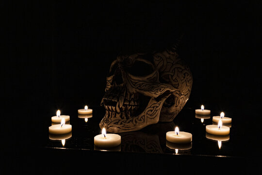 Teschio illuminato da candele con sfondo nero