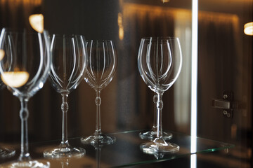 Wine glasses on a glass shelf with lighting.