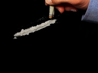 Businessman use 50 euro banknote to snorting cocaine drug powder lines on black table