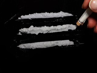Man use 50 euro banknote to snorting cocaine drug powder lines on black table