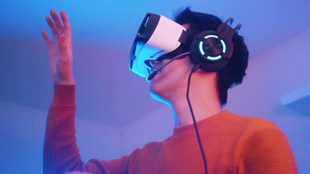 Virtual reality. Young man with VR headset touching something in the simulation. High quality 4k footage