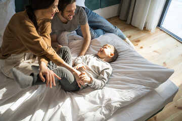 Boy laughing while his parents tickling him