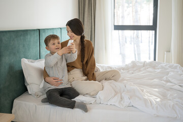Boy sitting at the bed with his young mother