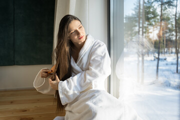 Woman checking her hair tips near the window