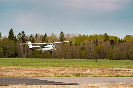 a light small plane flies against the background of a forest not high above the ground