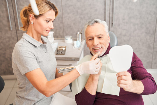 Dentist choosing shade for senior male patient teeth