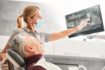 Dentist showing at the x ray and explaining