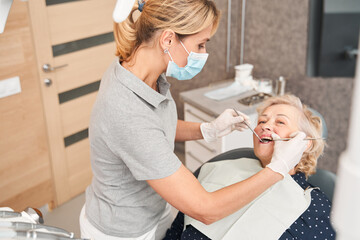 Woman having her teeth examined by serious doctor