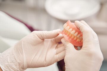 Dentist holding dentures in her hands - 415487091