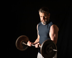 Strong, active, middle aged man with gray beard lifting heavy weights in studio setting, 2 thirds profile view.