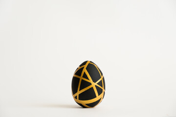 Easter golden egg with geometric black pattern isolated on white background. Minimal easter concept. Happy Easter card with copy space for text. Top view, flatlay. Concept for banner, flyer