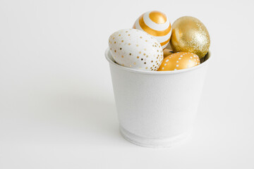 Easter golden decorated eggs in bucket on white background. Minimal easter concept. Happy Easter card with copy space for text