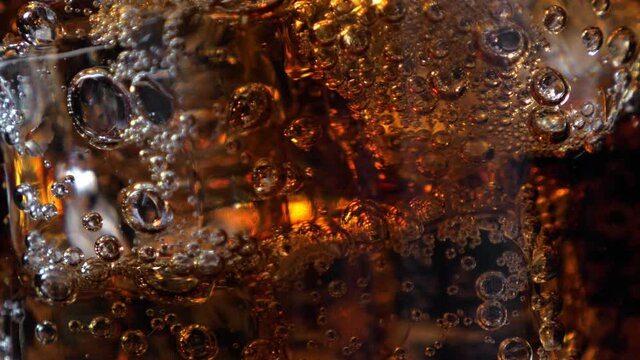 Fizzling cola in the glass. Closeup on black background