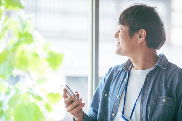 服装自由な会社でスマホを使う会社員

