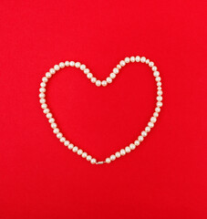 Heart of pearl beads on a red background