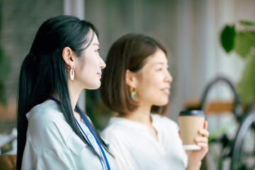 ホットドリンクを飲んでおしゃべりする女性
