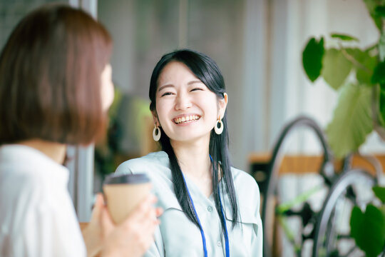 ホットドリンクを飲んでおしゃべりする女性
