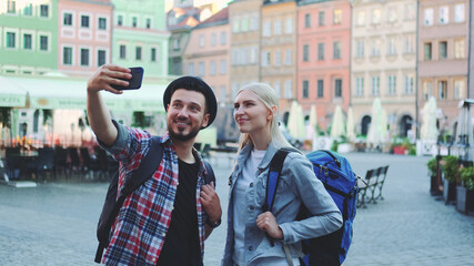Couple of tourists making selfie on smartphone in the city center. They have tourists bags.