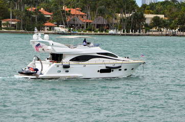 White motor yacht cruising by Star Island on Biscayne Bay.