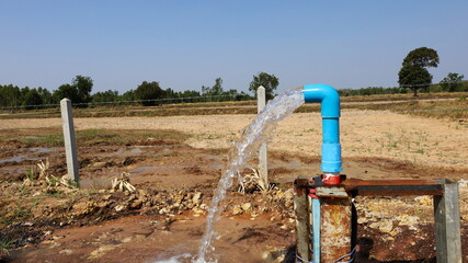 Water flow from blue water pumping pipe. Silver high water pressure gushing from plastic pipe of...