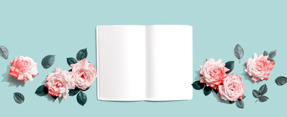 White blank notebook with pink roses overhead view - flat lay