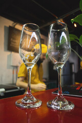 Dos copas vacías con residuos de cerveza sobre una barra, de fondo un chef mesero, un refrigerador y un menú