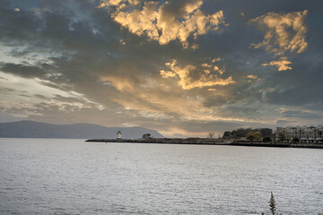 Sunset view of Sleepy Hollow lighthouse and buildings in Tarrytown over Hudson River on a cloudy day