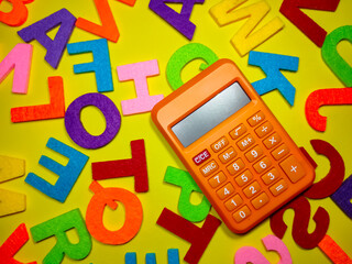 Selective focus.Calculator and colorful word on yellow background.Shot were noise and film grain.