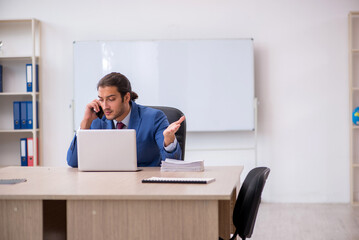 Young male employee sitting in the office in front of whiteboard