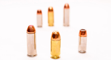 Six bullets, 9mm, 45 caliber and 44 special caliber with three being in the foreground and three blurred in the background on a white background
