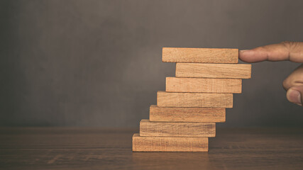 Close-up fingers prevent the wooden block from falling domino concepts of financial risk management...