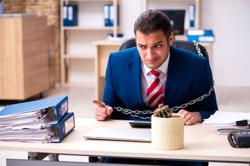 Chained male employee working in the office