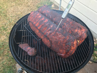 Pork Ribs smoking on outdoor grill with thermometer probing temperature