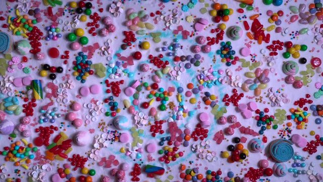 Candy in variety of colour, shape, size and flavours mixed on the table with real white sugar. Sweet stock of snack, chocolates, caramels, candy, jelly beans, icing, sugar and cake sprinkles.