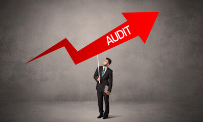 Obraz premium Young business person in casual holding road sign with AUDIT inscription, business direction concept