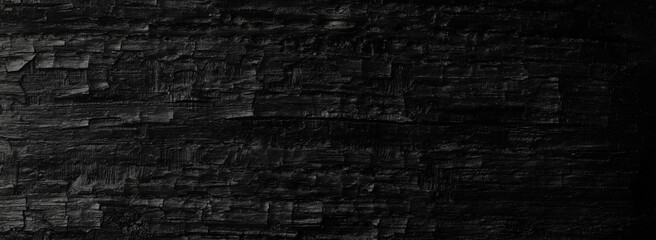 Dark black background of rough burnt wood, soot, and ash. Burn texture.