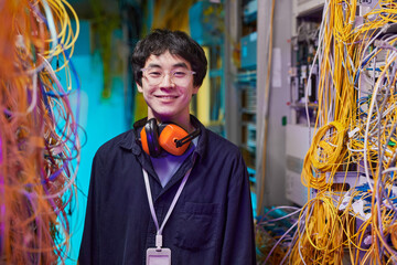 Waist up portrait of young network technician smiling at camera while posing in server room, copy...