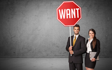 Young business person holding road sign with WANT inscription, new rules concept