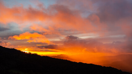 High viewpoint of an intense orange sunset with clouds and rain in the cloud forest, Dota, Costa Rica highlands