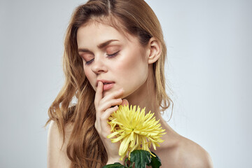 Portrait of a beautiful woman with a yellow flower on a light background charming smile model red hair